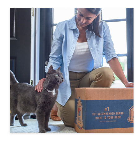 Eine Frau mit ihrer schwarzen Katze und einer Packung Katzenfutter von Hill’s